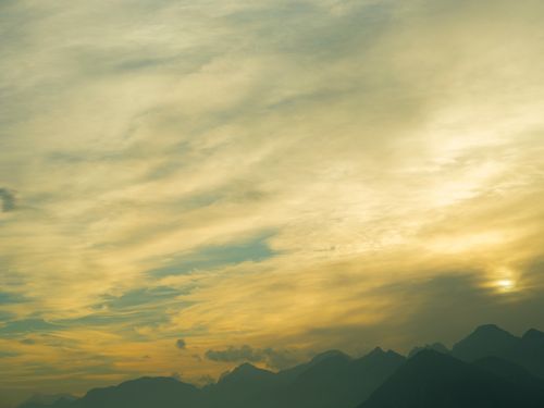 Free A tranquil cloudy sky over mountains at sunset, evoking a moody atmosphere. Stock Photo