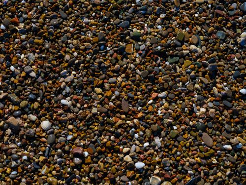 Free A vibrant collection of mixed pebbles on a beach providing a colorful texture. Stock Photo