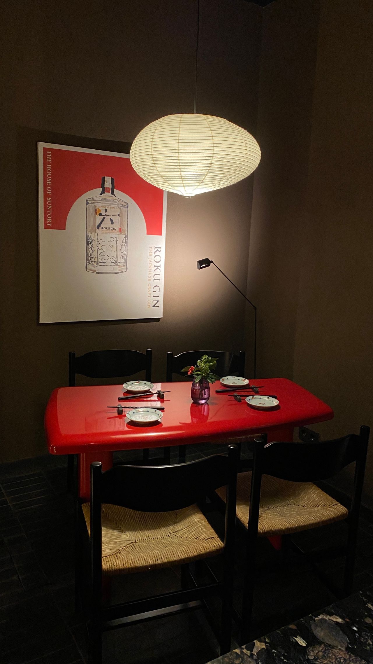 Red dining table with chairs and a hanging lantern