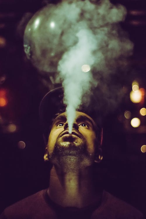 Free Man Wearing Crew-neck Shirt and Fitted Cap Smoking Stock Photo