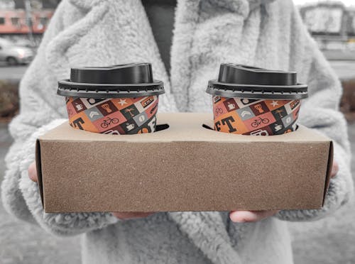 A Person Holding a Box with Coffee in Disposable Cups with Lids