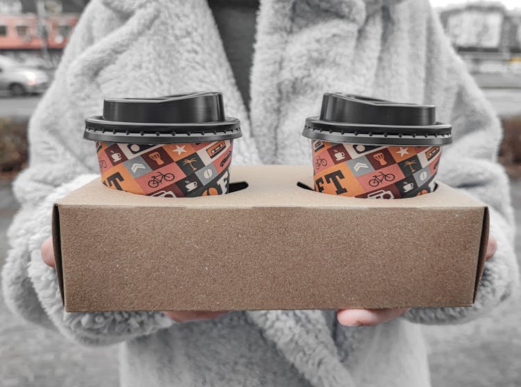 A Person Holding A Box With Coffee In Disposable Cups With Lids