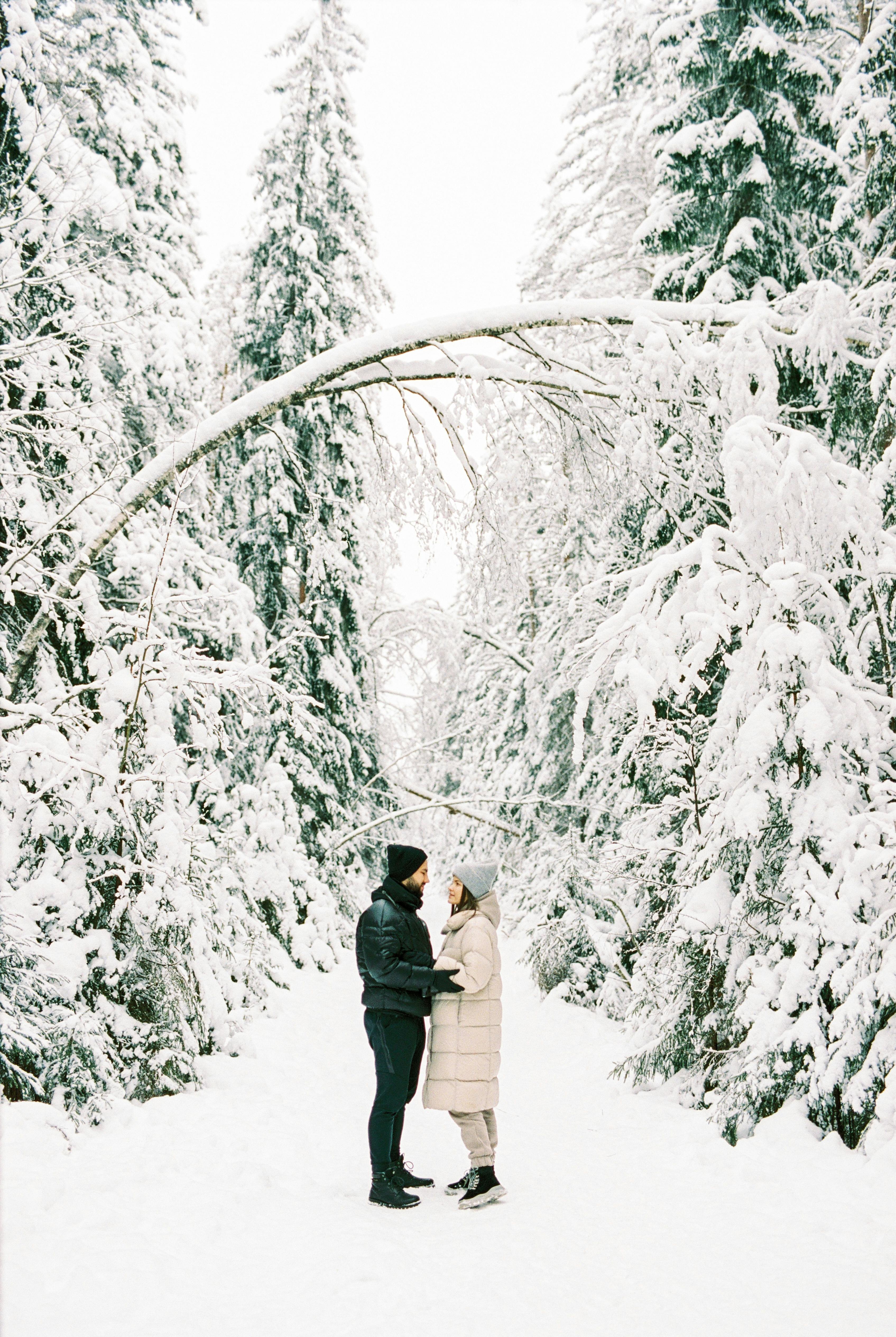 a couple holding hands in a snow covered forest