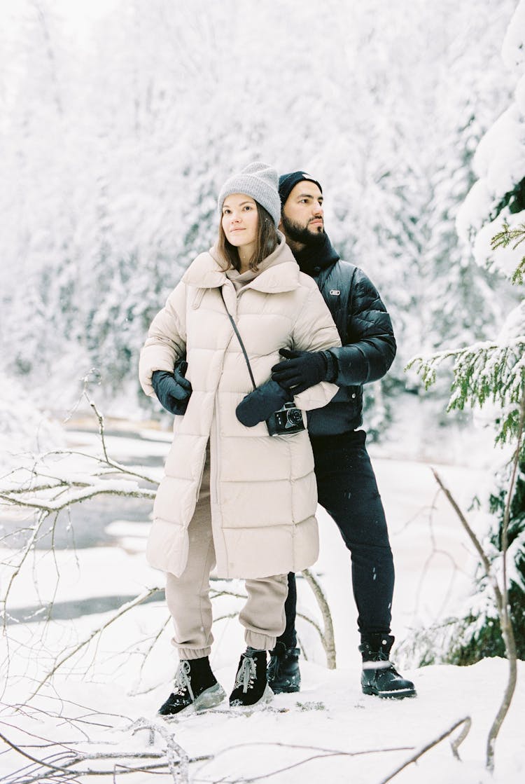 A Couple Embracing With Winter Forrest In The Background