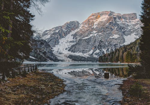 白雪皑皑的山脉倒映在森林环绕的宁静高山湖泊中，景色令人惊叹