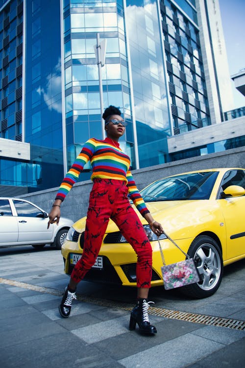 Femme Portant Un Pull Multicolore Et Un Jean Rouge Près Du Véhicule Jaune