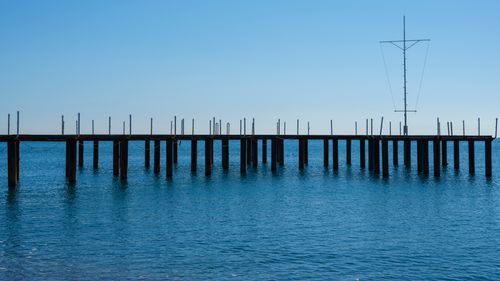 Free Peaceful scene of a wooden pier extending into the tranquil blue ocean waters. Stock Photo