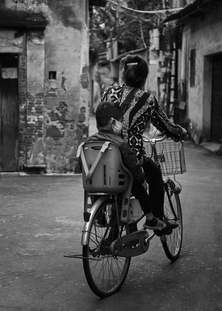 Grayscale Photo Of Mother And Son Riding Bicycle