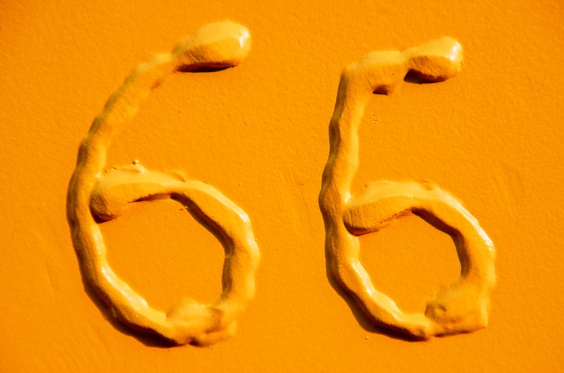 Close-up of textured number 66 in bold yellow with a smooth background