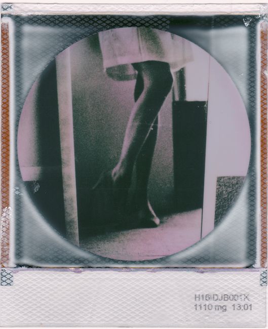 Artistic vintage Polaroid featuring a silhouette of legs in an indoor setting.
