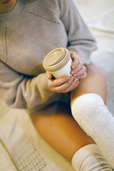 A woman in a cozy sweater holding a hot drink, perfect for autumn moments.