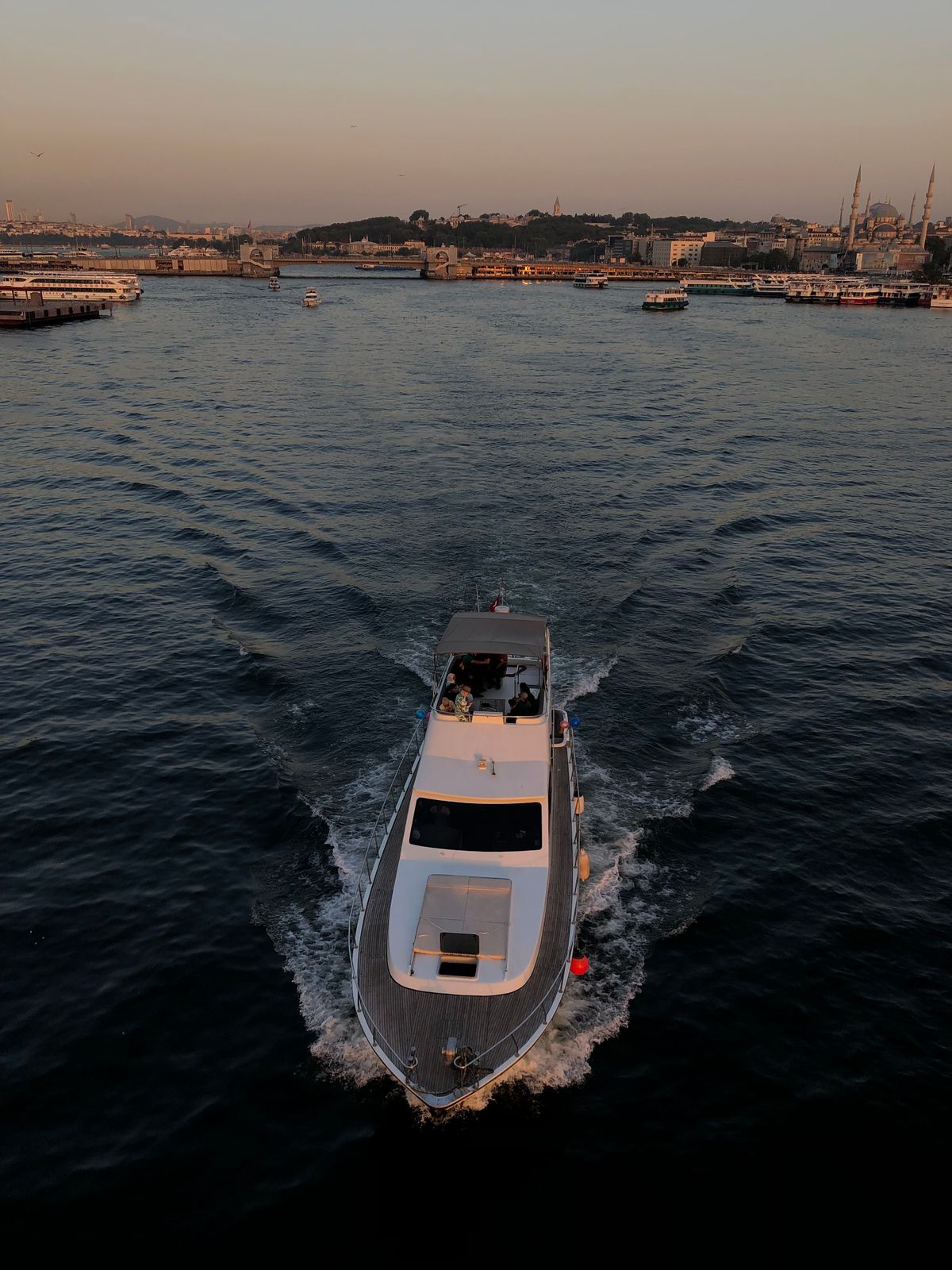 Yacht cruising past a city skyline at sunset