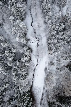 Aerial view of a snow-covered forest and stream in Ilmenau, Germany.