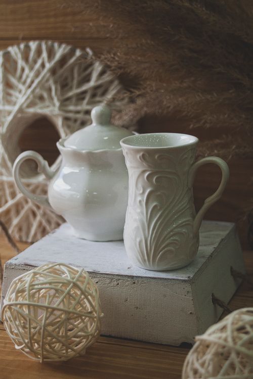 Free A classic still life of an ornate ceramic teapot and mug with textured wicker accents. Stock Photo