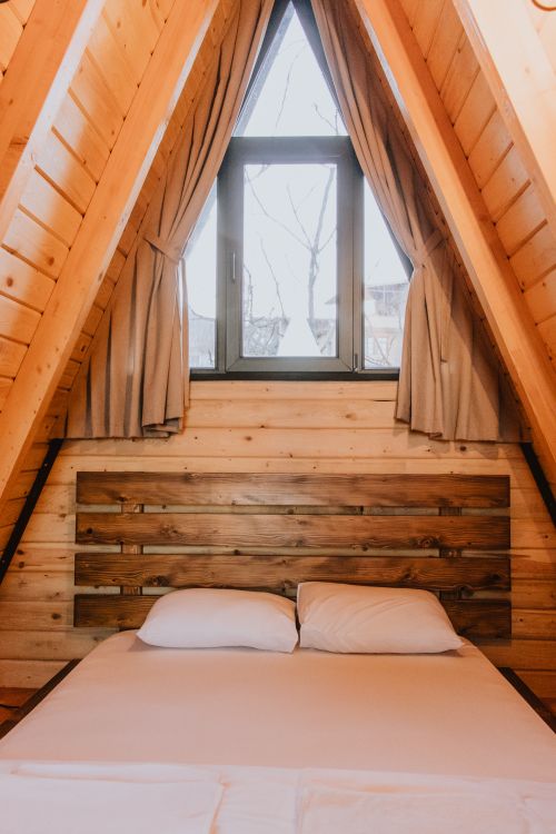 Free A charming rustic bedroom with wooden interiors in an A-frame cabin style architecture. Stock Photo