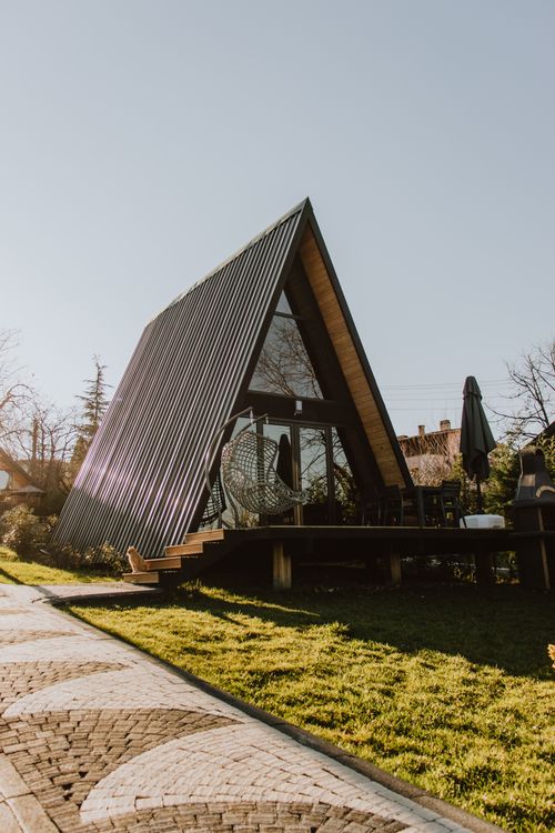 Free A charming A-frame cabin in a sunlit, rustic setting, ideal for retreats. Stock Photo