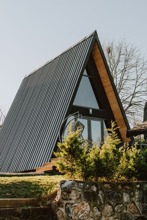 Free A serene A-frame cabin with modern design amidst greenery, evoking a rustic charm. Stock Photo