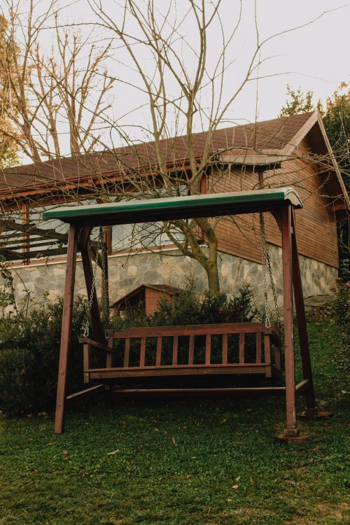 Free A cozy wooden swing bench in a tranquil backyard garden, perfect for relaxation. Stock Photo