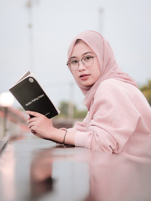 Free Woman in Pink Hijab Holding Black Book Stock Photo