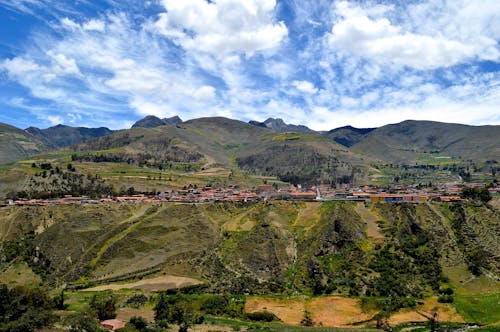 Birdseye Photography of Buildings Near Hills and Trees Under Blue Sky