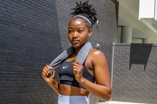 Free A Woman Wearing a Sports Bra while Standing Near the Gray Brick Wall Stock Photo