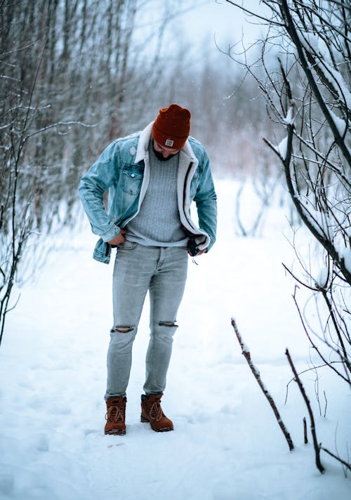 A Man in Denim Jacket and Pants Standing on a Snow Covered Ground