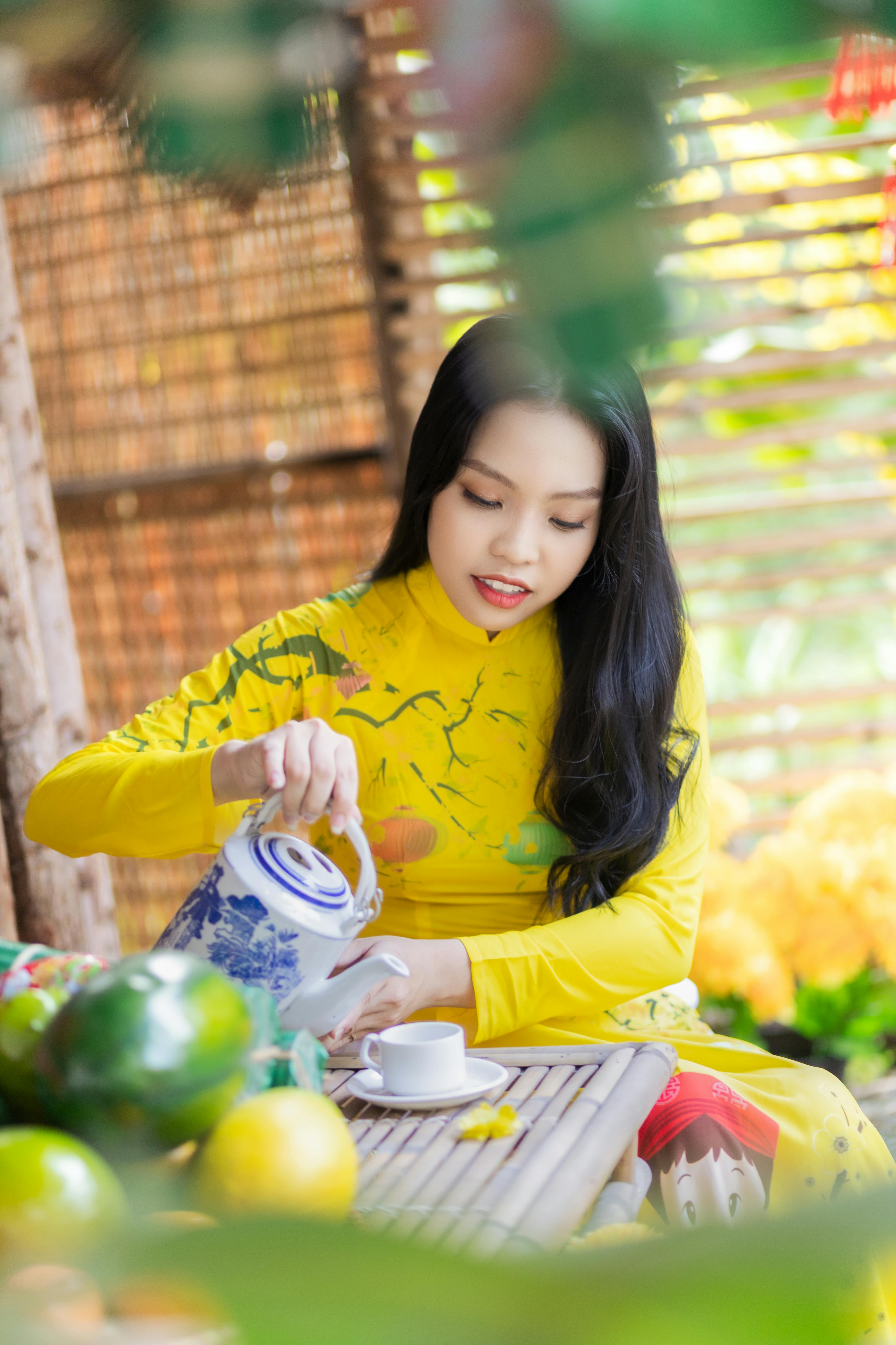 Captivating image of a Vietnamese woman in ao dai pouring tea, highlighting tradition.