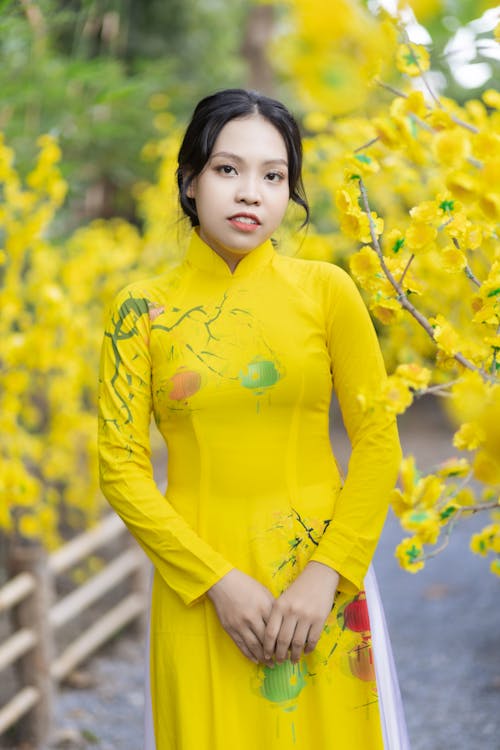 Woman in Yellow Long Sleeve Dress Near Yellow Flowers