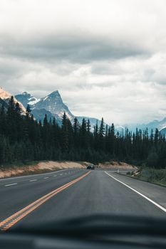 A scenic drive through the Canadian Rockies with towering mountains and lush forests.