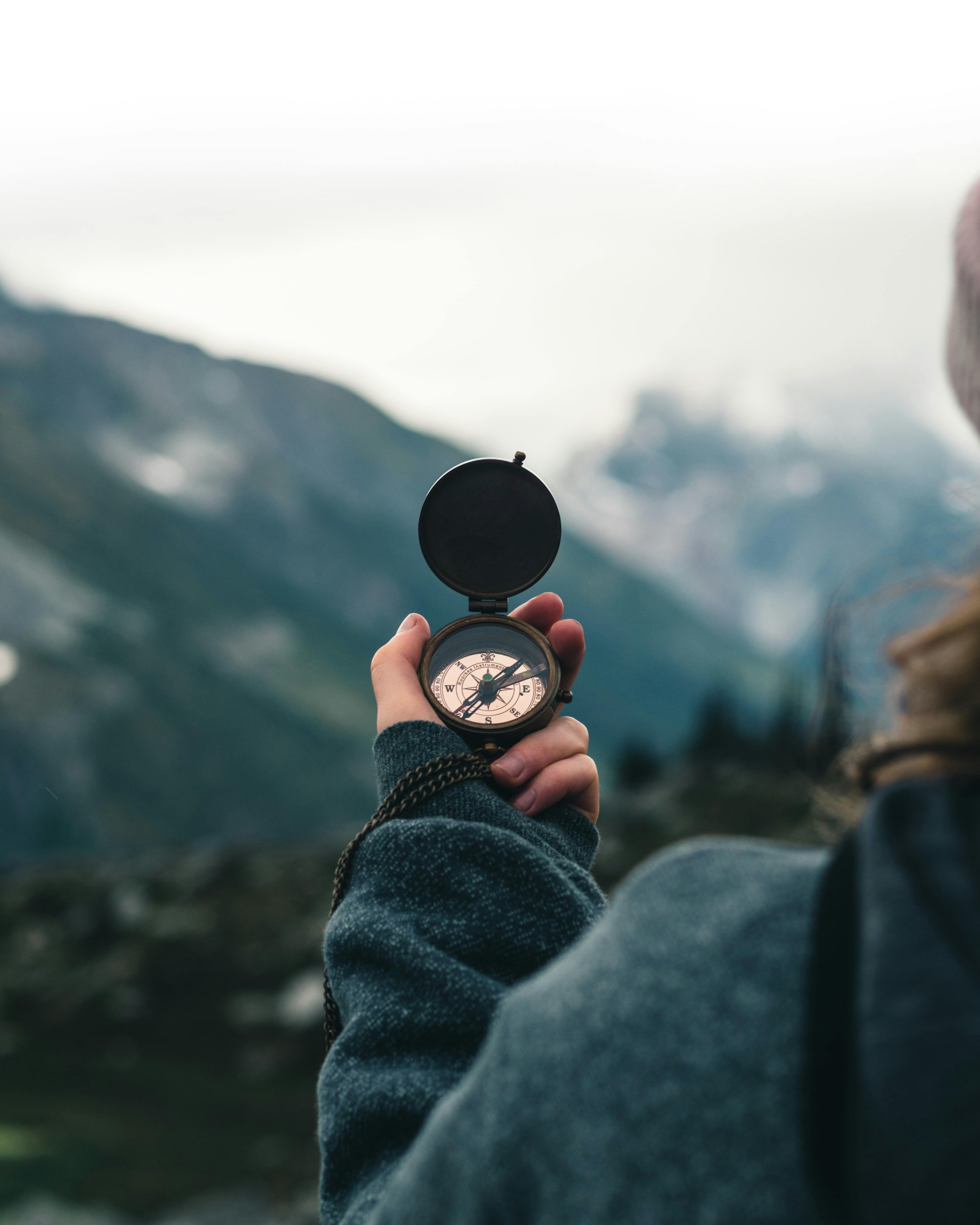 Una persona sosteniendo una brújula en medio de las montañas escénicas de Columbia Británica, Canadá.