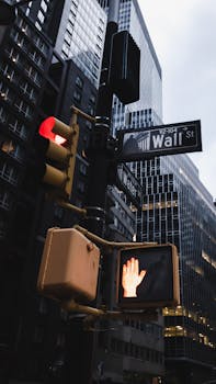 Urban view of Wall Street skyscrapers with a traffic signal at dusk.