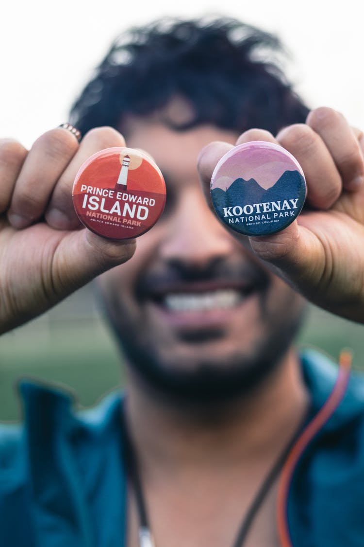 A Man Holding Two Round Button Pins