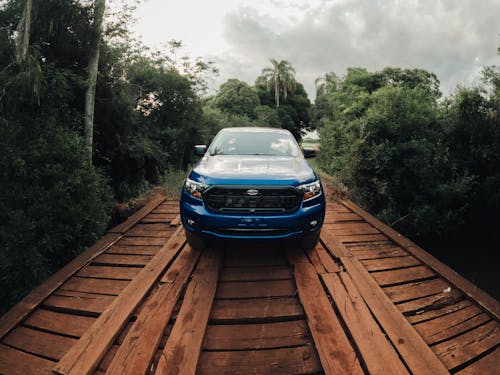 A Blue Car Parked on a Wooden Bridge