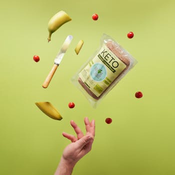 Floating keto bread with bananas, knife, and cherry tomatoes on a vibrant background.
