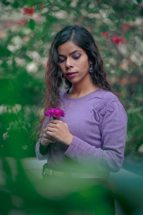 A Woman in Purple Long Sleeves Holding Purple Flowers