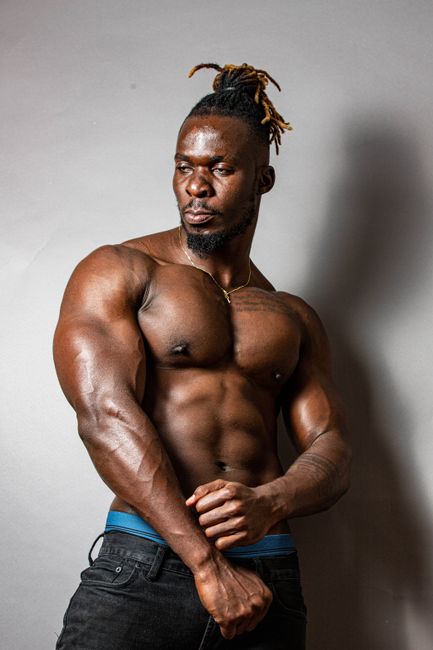Muscular African American man showcasing strength in a striking pose. Muscular African American man showcasing strength in a striking pose.