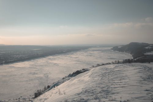 Free Aerial view of a snowy river landscape with mountains in winter. Stock Photo