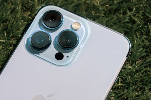 Detailed close-up of smartphone camera lenses on green grass background.
