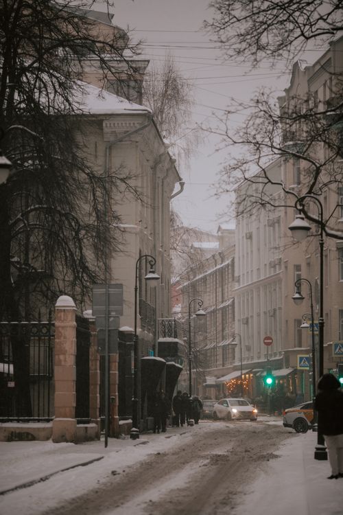 Free A serene winter scene capturing a snow-covered street with beautiful buildings in an urban setting. Stock Photo