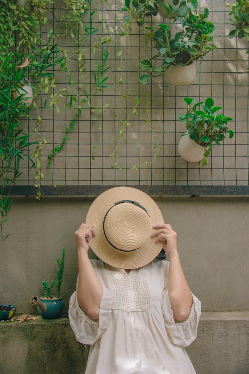 Person Wearing White Elbow-sleeved Top Covering Beige Sun Hat
