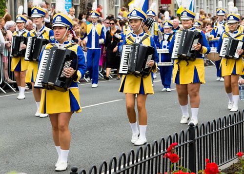 Free Vibrant street parade featuring musicians in colorful uniforms playing accordions. Stock Photo