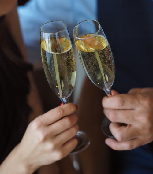 Close-Up Shot of Two People Holding Glasses of Liquor