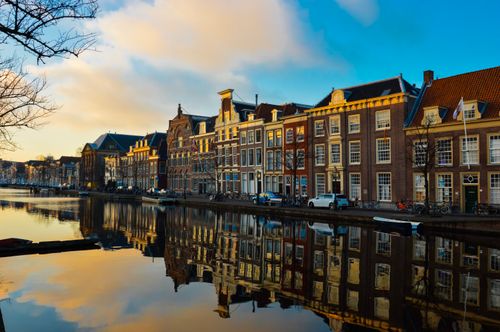 Free Beautiful reflection of traditional Dutch buildings on a canal during sunset. Stock Photo
