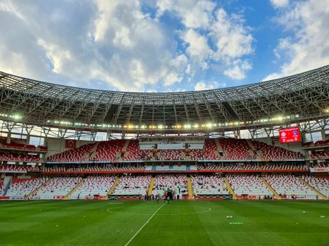 A scenic view of a modern stadium in Antalya, Turkey, under a vibrant blue sky.