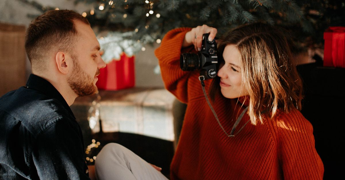 Rüyada Sevgilinizle Tatil Yolculuğuna Çıkmak - Rüya Tabiri ve Anlamı - A couple enjoying a cozy, affectionate moment by the Christmas tree, capturing memories.