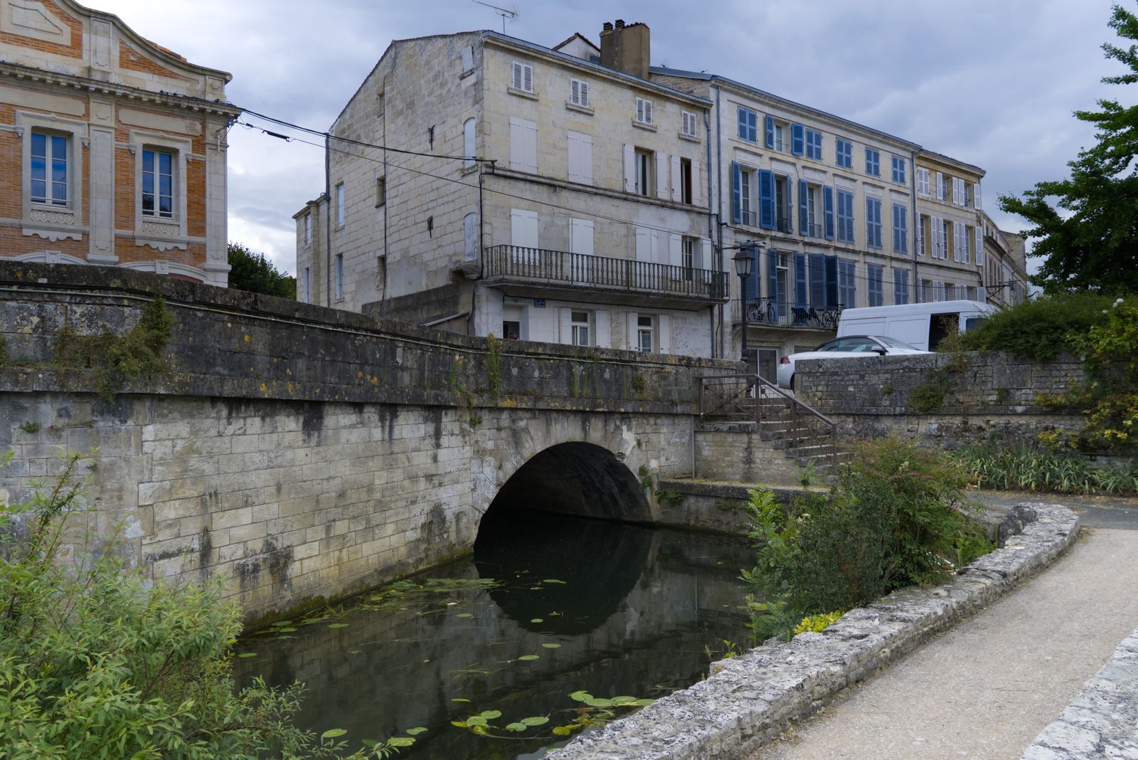Vieux pont de pierre en arche sur une petite rivière dans une ville en pierre calcaire