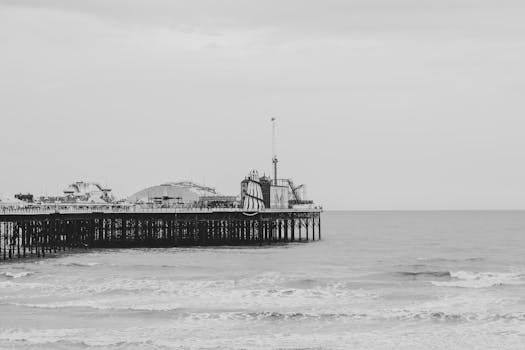 A grayscale image of a classic pier extending into the ocean, depicting serene seaside tranquility.