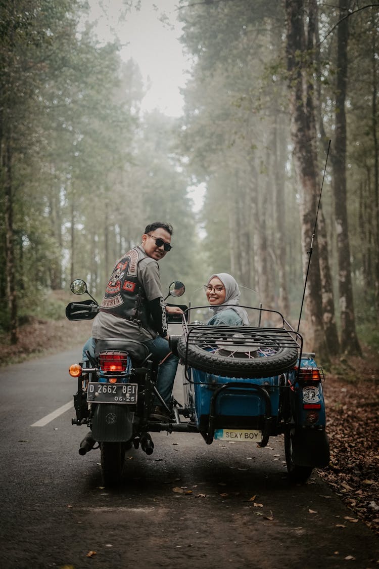 A Man And A Woman Riding A Motorcycle With Sidecar On A Foggy Road