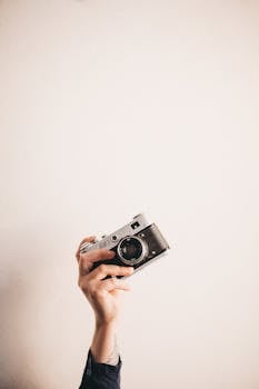 Close-up of a hand holding a classic vintage camera with ample white copy space, highlighting simplicity and nostalgia.