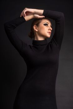 Stylish portrait of a woman in a black dress with arms gracefully posed.